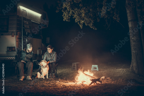 Couple on vacantion near campfire and motorhome