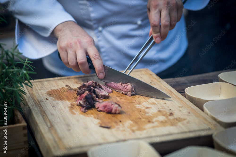 chef cutting meat with knife on cutting board