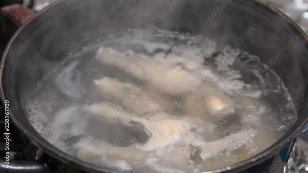 A lot of chicken legs boiling. broth is cooked in a saucepan