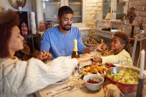 family having Christmas prayer for dinner at home.