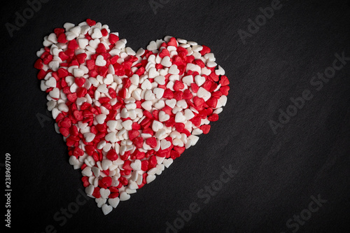 big heart from many heart-shaped candies on black backdrop
