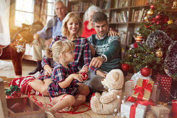 holidays and celebration concept - happy family decorates a Christmas tree.