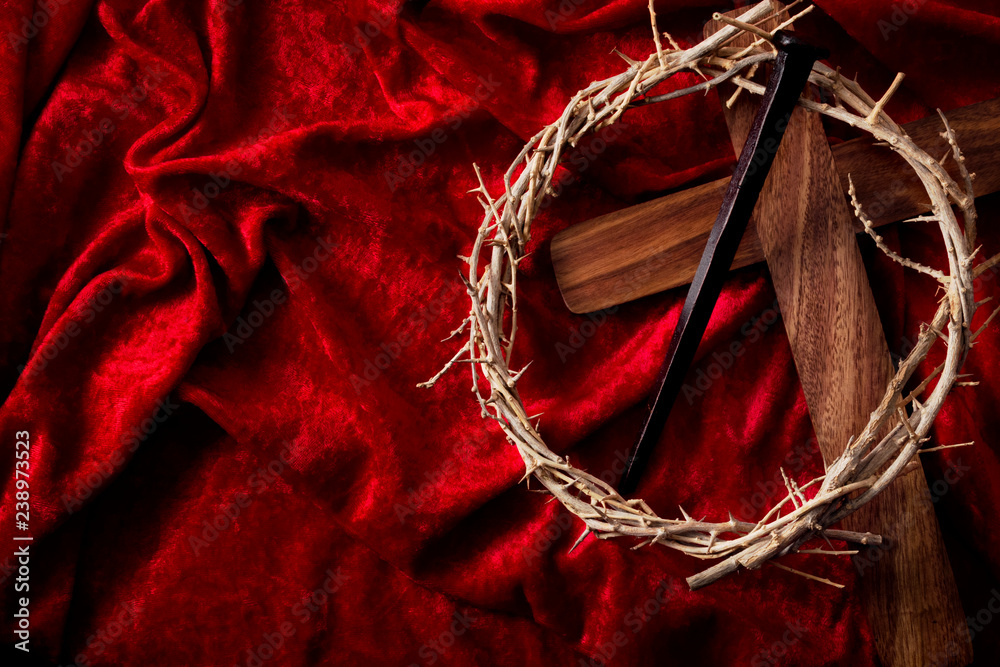 Easter holiday, reminder of the sacrifice of the Lord and Savior Jesus Christ concept with wooden cross, crown of thorns and rusty Crucifixion nail isolated on a red velvet background with copy space