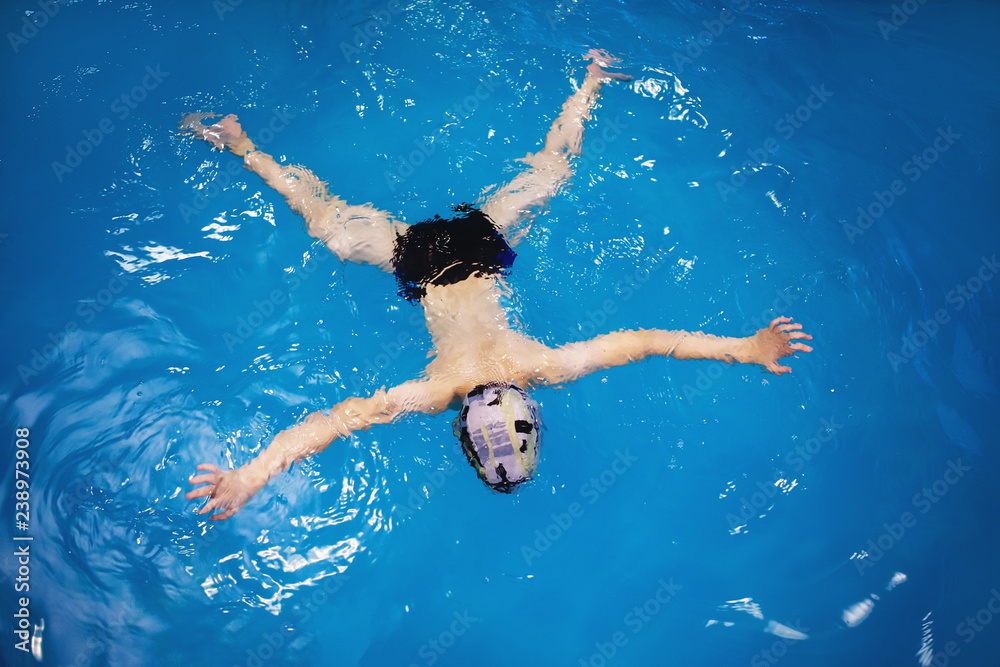 Boy in a swimming cap swims in a pool. Boy in a swimming cap swims in a pool.