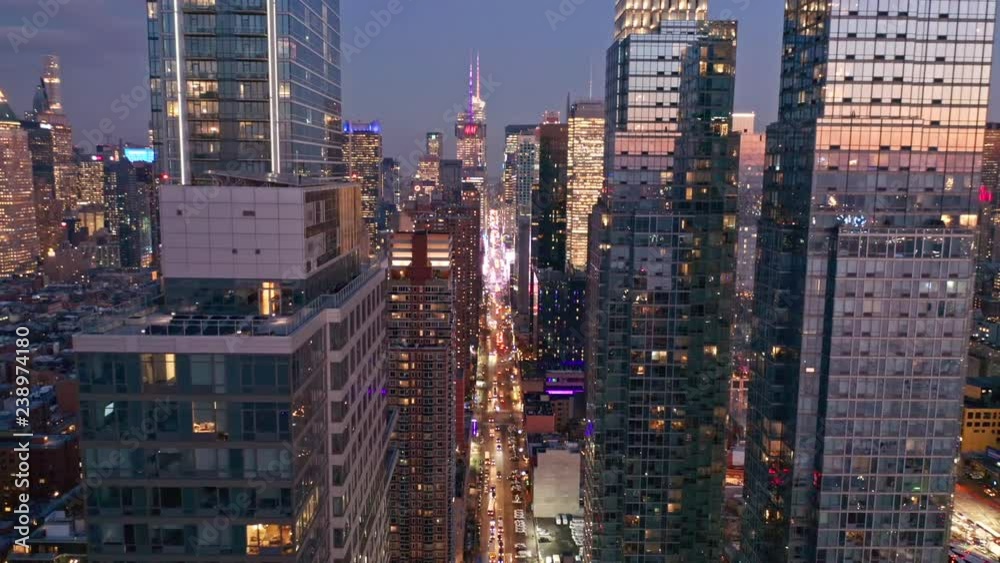 Aerial drone footage of New York skyline along 42nd street canyon, at dusk, with pull back camera motion