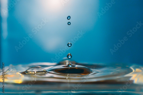 Splash photography  drops falling down into the water in a blue lighted background