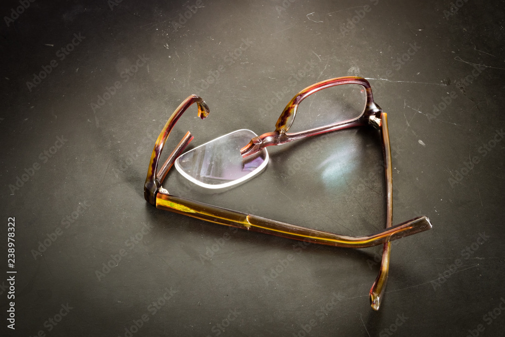 Foto de Broken eyeglasses on desk; lens of glasses fell out of broken