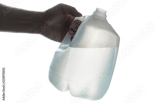Hand holding 1 gallon plastic bottle of drinking water; silhouette on white. photo
