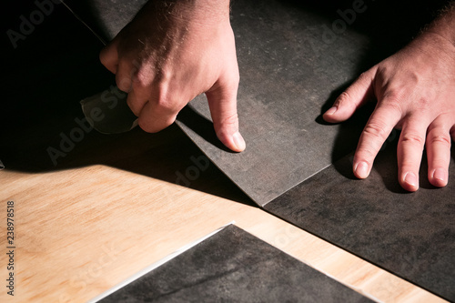 Hand installation of vinyl flooring tiles.