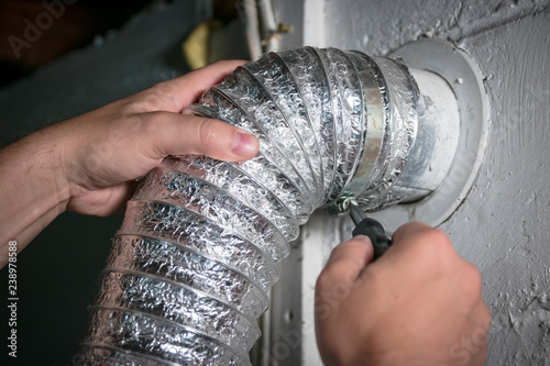 Foto Flexible dryer vent hose, attaching/detaching from wall vent by turning screw in steel duct clamp