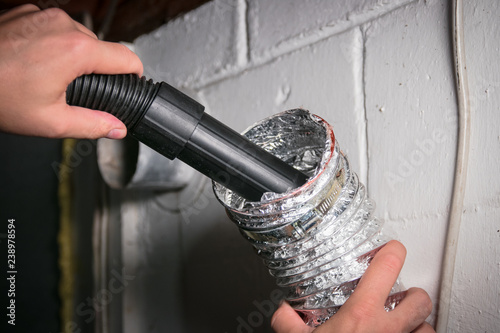Vacuum cleaning a flexible aluminum dryer vent hose, to remove lint and prevent fire hazard. photo