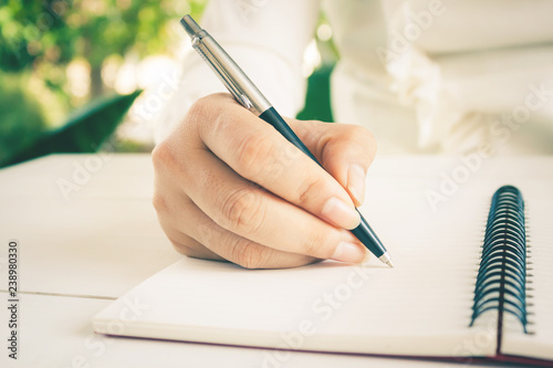 Woman hand with pen writing on white notebook. with copy space.
