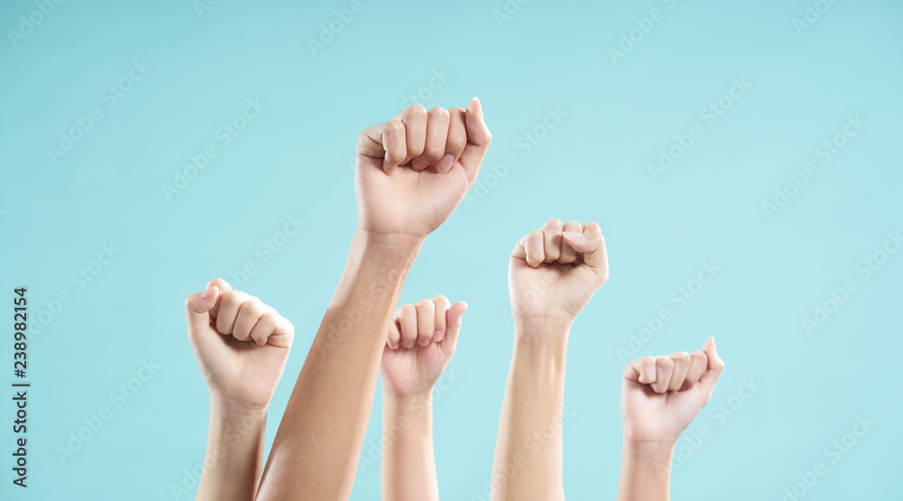 Multiethnic male and female hand raised against a blue background Multiethnic male and female hand raised against a blue background