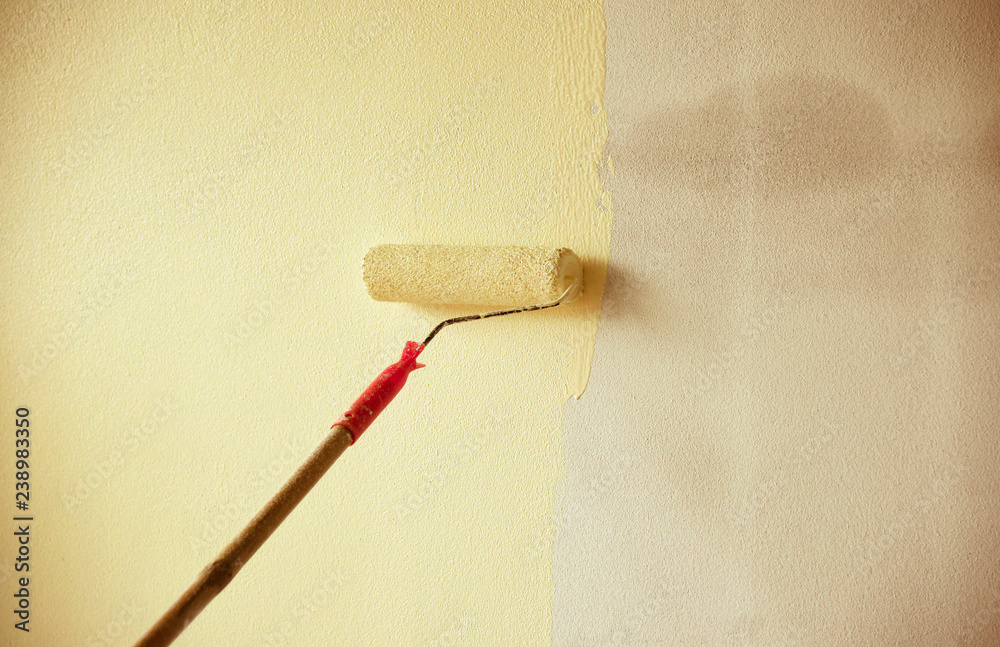 painted wall background / hand painting wall with paint roller on building construction painted wall background / hand painting wall with paint roller on building construction