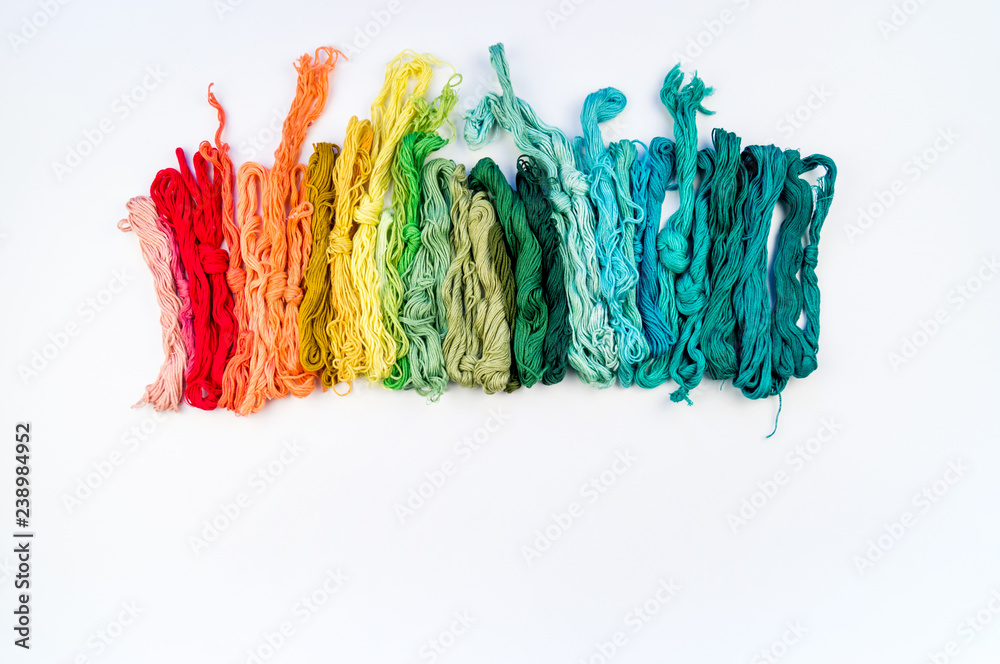 Rainbow color threads for embroidery on a white background.