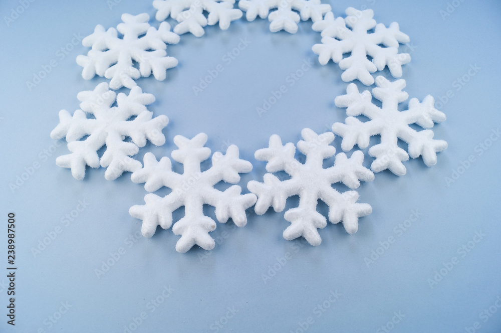 A wreath in a circle of decorative snowflakes on a blue background. A wreath in a circle of decorative snowflakes on a blue background.