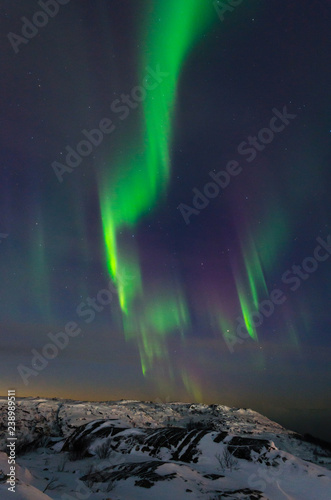 Fototapeta Naklejka Na Ścianę i Meble -  Beautiful northern lights, aurora in the night sky over the snow-covered hills.
