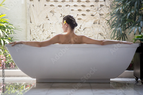 Portrait of a young woman relaxing in the bathtub, organic skin-care at the luxury hotel spa, wellbeing and self-care concept