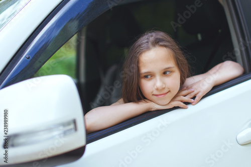Girl teenager with long hair looks out the window of the car.