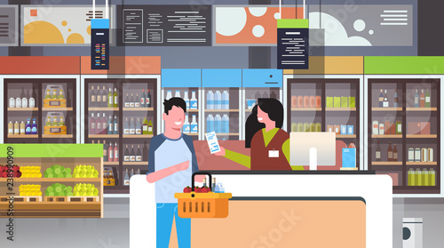 retail woman cashier at checkout supermarket giving receipt bill man customer holding basket with food shopping concept grocery market interior flat horizontal