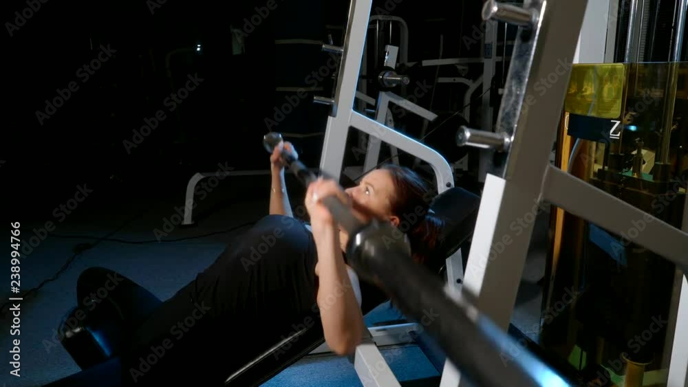 The girl is engaged in the gym Exercise on the pectoral muscles. Bench press lying on the chest. 4k