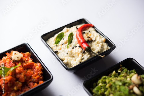 Group of Indian Chutneys includes coconut, Peanut, green and red chilly, garlic and pudina served in small square shape bowls. selective focus photo