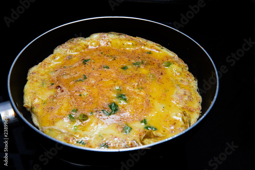 cooking omlette in Indian style with green chili , corriander leaves and lot of spices in a non stick pan
