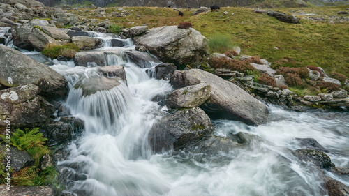 Moody landscape image of river flowing down mountain range near Llyn Ogwen and Llyn Idwal in Snowdonia in Autumn