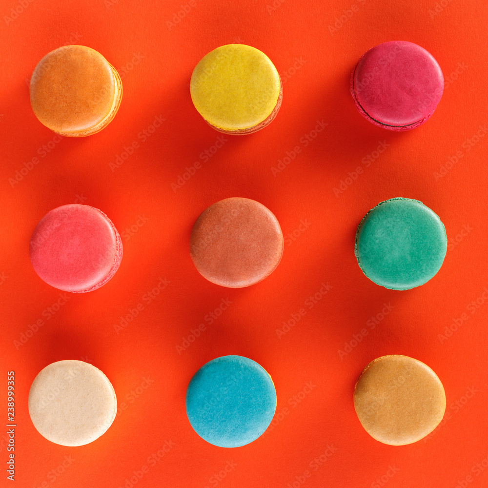 Creative layout of colorful macaroons on a red background. Flat lay. Nutrition concept.