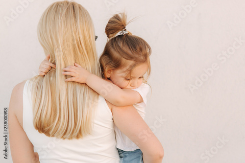 Beautiful mothe with her daughter. Blond hair female. Gray background. Best friends
