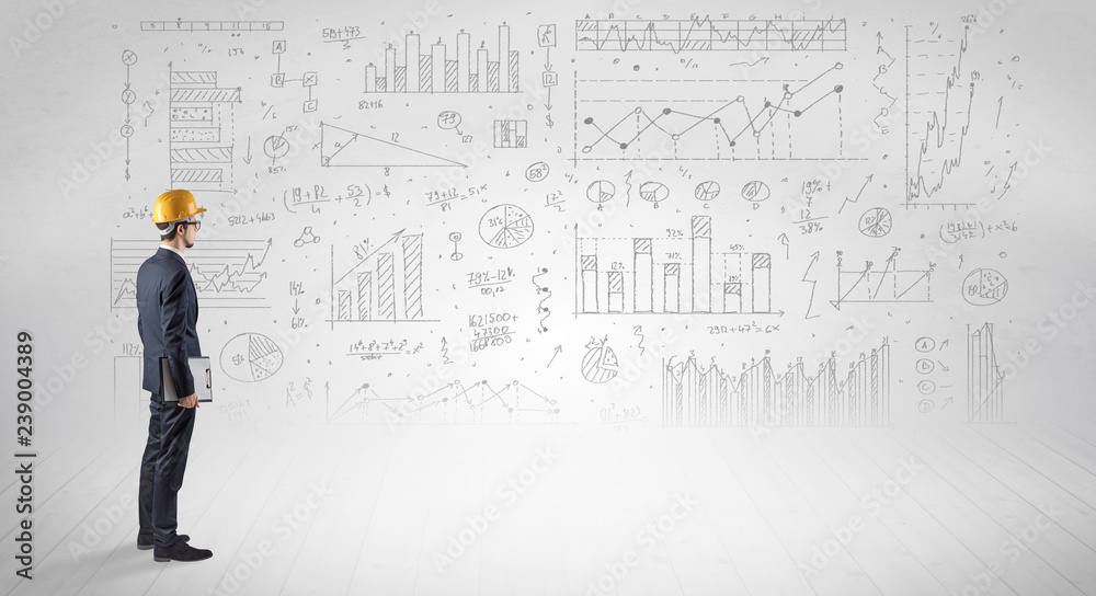 Engineer with construction helmet holding a plan and standing with graphs, charts and reports on the background Engineer with construction helmet holding a plan and standing with graphs, charts and reports on the background