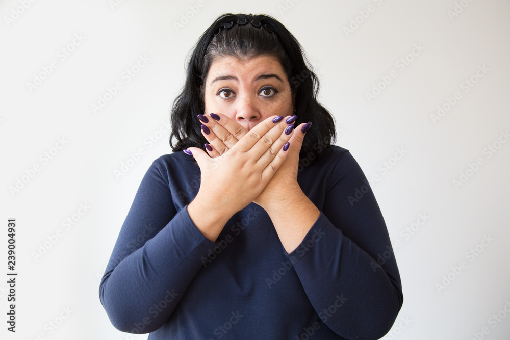 Hispanic overweight stressed woman covering mouth. Surprised woman looking at camera. Isolated on white. Shock concept Hispanic overweight stressed woman covering mouth. Surprised woman looking at camera. Isolated on white. Shock concept