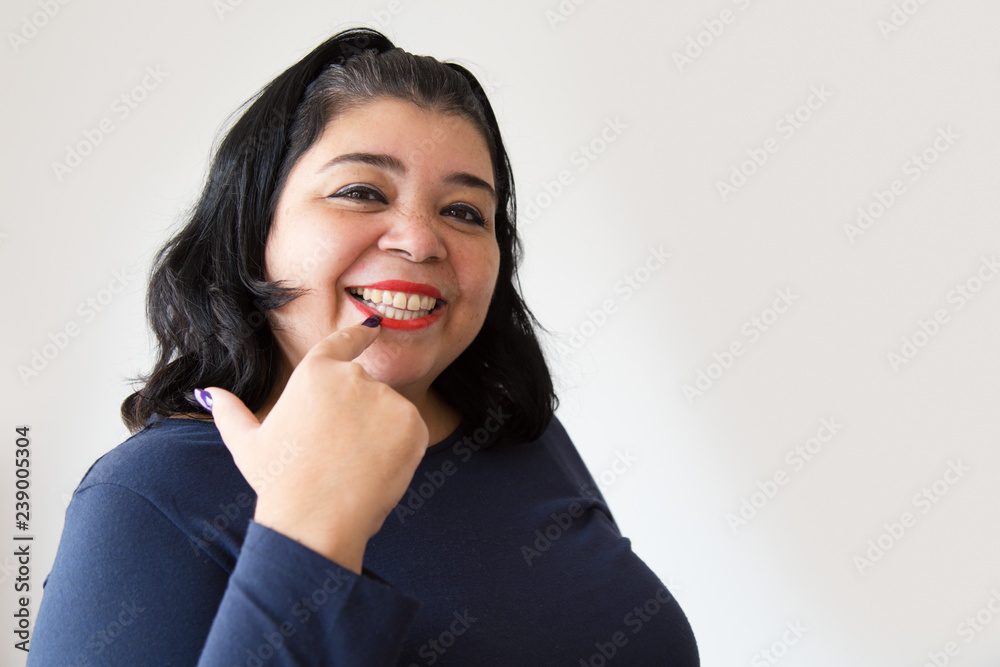 Smiling Hispanic woman pointing at teeth. Happy positive woman showing smile with finger. Isolated on white. Dental hygiene concept Smiling Hispanic woman pointing at teeth. Happy positive woman showing smile with finger. Isolated on white. Dental hygiene concept