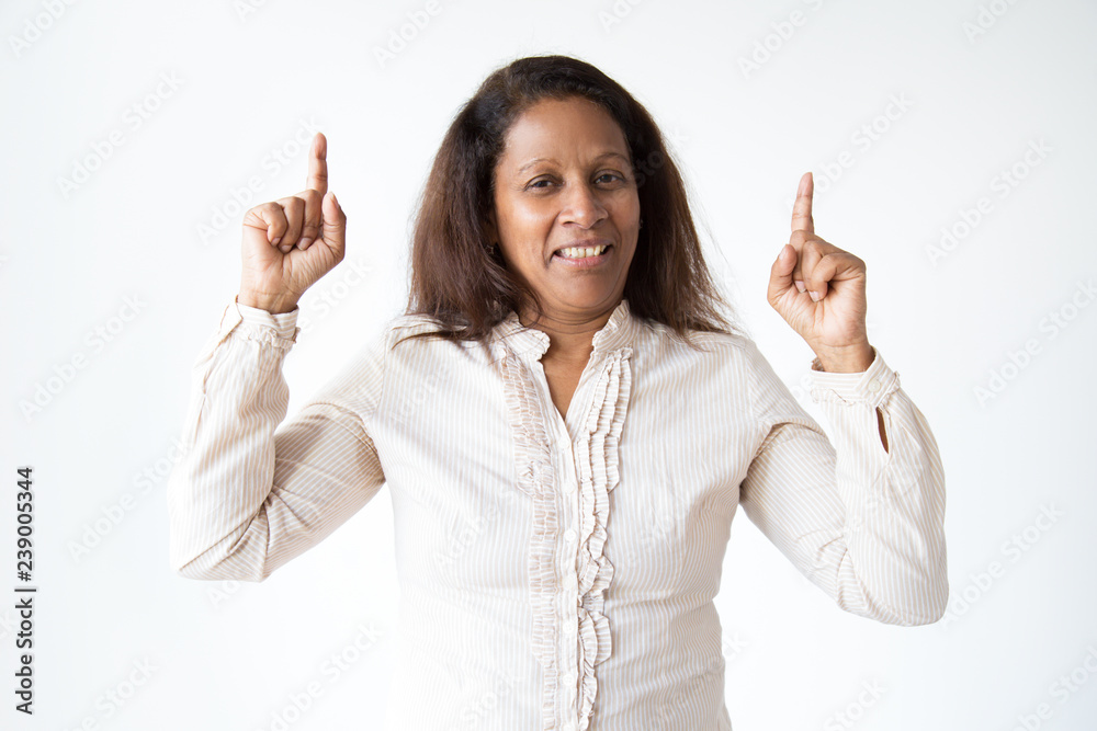 Smiling Indian woman pointing up on advertisement, studio portrait. Cheerful mature woman in blouse having new idea. Isolated on white. Advertisement concept Smiling Indian woman pointing up on advertisement, studio portrait. Cheerful mature woman in blouse having new idea. Isolated on white. Advertisement concept