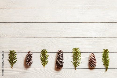 White wooden christmas background with fir branches and cones, top view, copyspace. © MaximBeykov