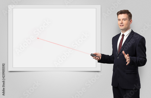 Young businessman with laser pointer and copyspace white blackboard