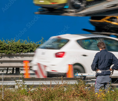 Police officer with speed camera monitors the speed of vehicles on the edge of the highway photo