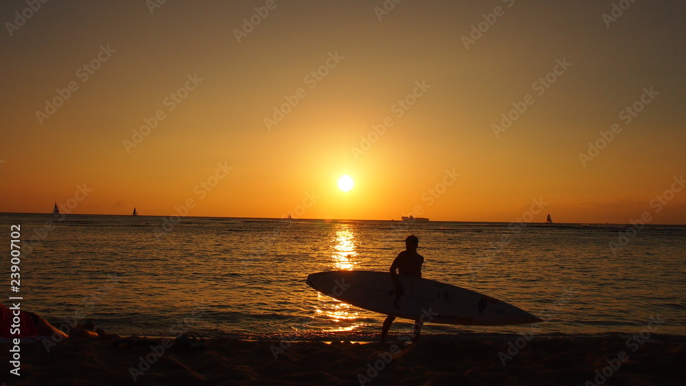 ワイキキビーチの夕日とサーファー