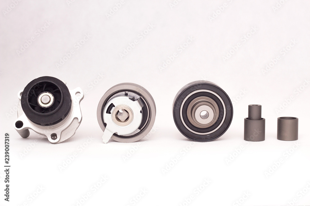 Set of rollers of the automobile engine timing system and the cooling pump on a white background, closeup Set of rollers of the automobile engine timing system and the cooling pump on a white background, closeup