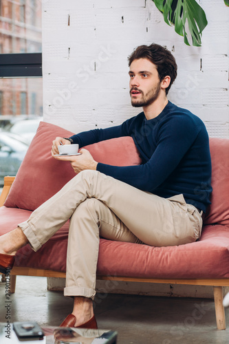 stylish attractive man is drinking coffee during the break. side view photo. lazy office worker © alfa27