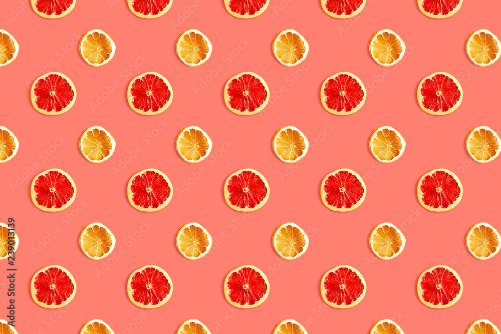 Creative pattern of dried slices of grapefruit and lemon on trendy coral background. Top view, flat lay style.