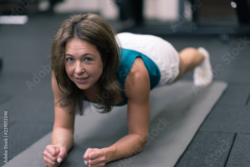 woman doing plank exercise on mat in gym