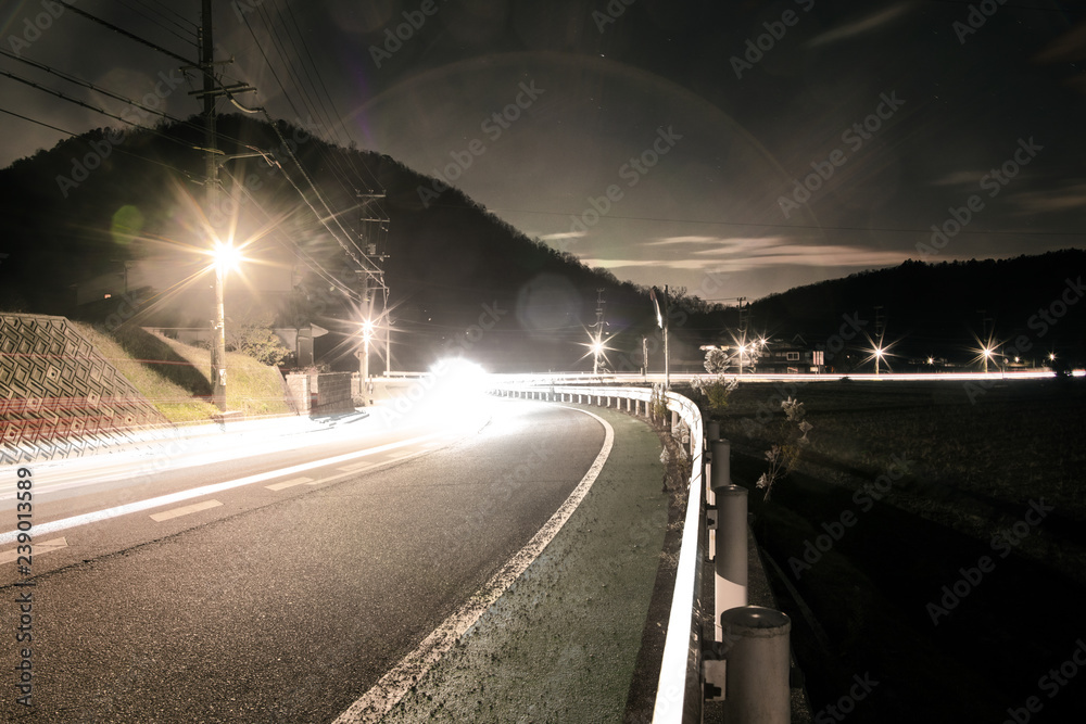 Bright headlights flare in the darkness on curved county road