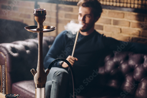 attractive young man in stylish clothes with hookah resting at the bar. close up shot. relaxation. rest concept