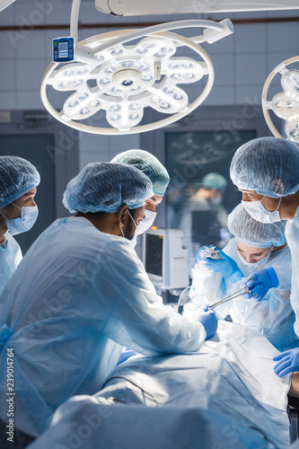 Canvas Print Diverse team of professional surgeons performing invasive surgery on a patient in the hospital operating room
