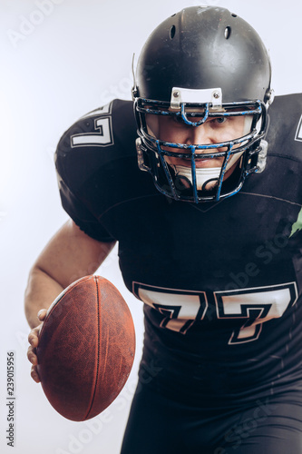 Emotional American football centre forward player in black protective uniform throwing a ball, isolated over white background