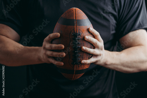 Rugby ball in muscular strong hands of caucasian player. Close up. photo