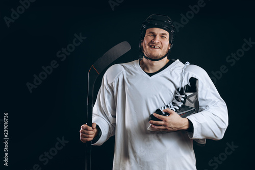 Photography Smiling hockey player looking at camera with skates over shoulder