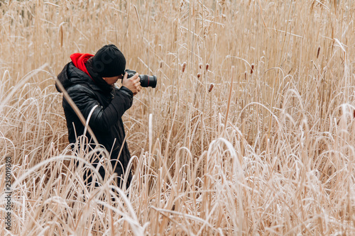 male photographer with a camera in the reeds in winter