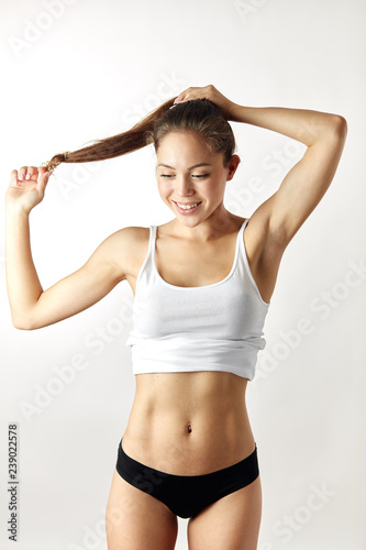 The fit woman doing her hair. girl making a pony tail in the morning. close up photo. isolated white background